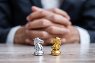 Gold and silver Chess Knight (horse) figure with businessman manager background. Strategy, Conflict, management, business planning, tactic, politic, communication and leader concept