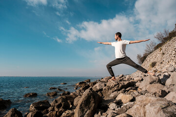 Attractive young man practicing yoga meditation and breathwork outdoors by the sea