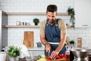 Portrait of handsome man in kitchen. Young man preparing salad.