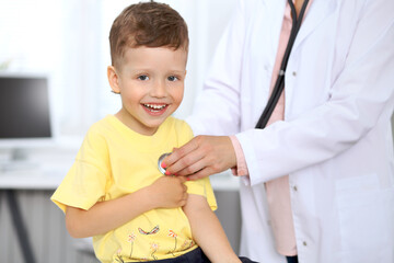 Happy little boy having fun while is being examine by doctor with stethoscope