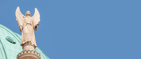 Banner with a statue of winged angel at Evangelical church Saint Nikolai at blue sky and copy space for text, Potsdam, Germany, details, closeup.