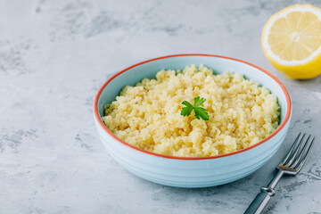 Cooked couscous in blue ceramic bowl on the table, copy space.