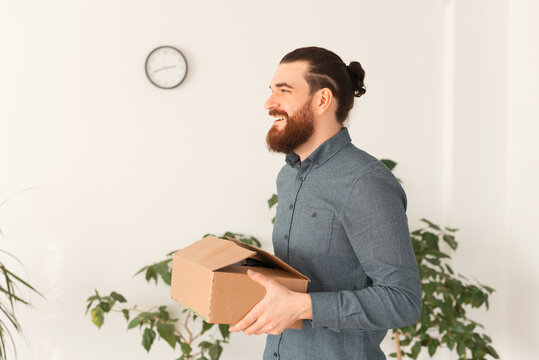 Photo of young smiling man moving to another office or job.
