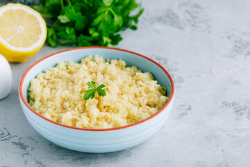 Cooked couscous in blue ceramic bowl on the table, copy space.