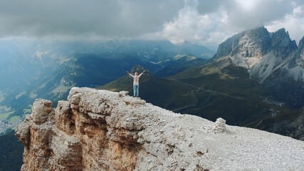 Naklejka na ściany i meble Stunning landscape of mountain rocks and woman standing on the top with outstretched arms. Freedom concept.