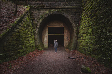 A young woman looks ahead into a dark, empty void that is the Neidpath Train Tunnel at Peebles,...