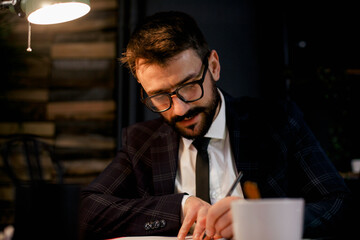 Young businessman using laptop in his office. Businessman taking a notes while working on laptop