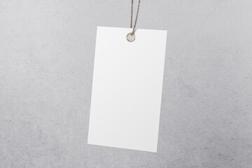Modern blank white paper label tag at abstract concrete background. Eco friendly hanging tag concept. Mock up. 3D rendering