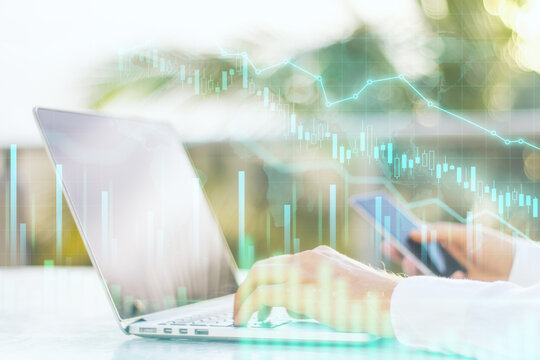 Working process: businessman with laptop and smartphone and glowing digital financial graphs. Double exposure.
