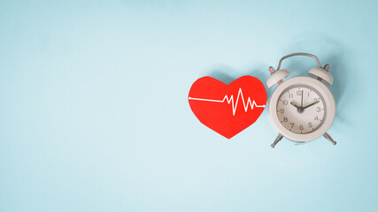 red heart with heartbeat and white analog clock on grunge blue paper background ,  health and...