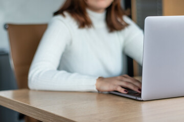 woman in white sweater working with laptop in office
