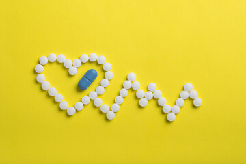 Heart of pills on a yellow background.