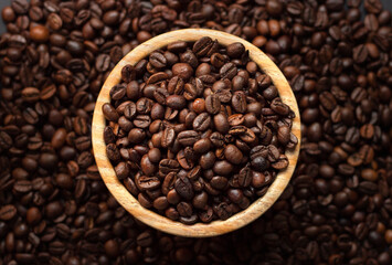 Bunch of coffee beans on a wooden bol with a coffee bean background for coffee lovers