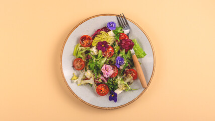 Vegetarian salad with tomato, lettuce, and cheese garnished with edible flowers. Spring food concept. 
