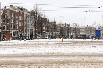 Fototapeta na wymiar Street View with Snow, People Walking and Canal Houses in Amsterdam