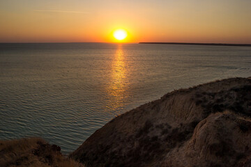 Sea side in sunset at summer vacation. Colorful sky at sunset on the horizon. Rising Sun Reflecting on Water with Calm Ocean Waves. Hope, spirituality, freedom - concept. Evening on the beach.