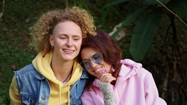 lesbian couple hugging in a sakura garden. Two women share love and support while holding hands. Gay Family. LGBT concept of friendship. cinematic chot bmpcc 6k