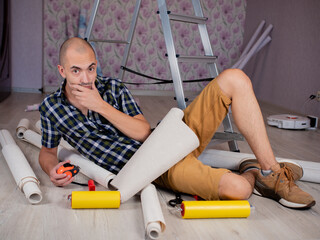 The man is confused about how to start repairing the apartment. The concept of wallpapering in the...