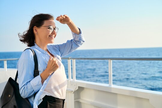 Beautiful happy mature woman on deck of ship, ferry, enjoying sea voyage