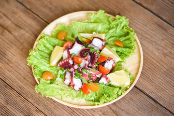 Octopus salad with lemon tomatoes and vegetables on wooden plate Fresh and healthy salad seafood squid and octopus.
