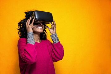 Beautiful young indian woman uses Vr glassess for augmented reality  - Pretty Sri Lanka girl uses technologic goggles posing with a yellow bright background