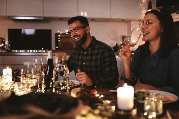 Friends laughing around a table during a candlelit dinner party