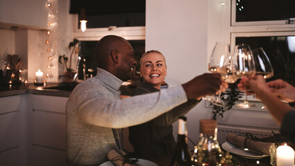Laughing couple toasting with friends at at a dinner party