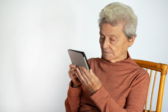 Senior woman sitting reading an e-book. Happy grandma reading e-book at home