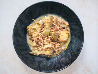 Plate of fregula, a typical sardinian pasta, with bio artichoke, Italian Cuisine. Vegan autumn plate