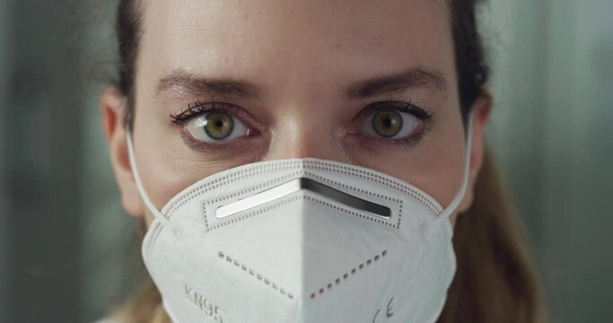 Cinematic macro shot of female pharmacist consultant taking off protective N95 respirator mask and smiling in camera in pharmacy. Concept of covid-19, protection, coronavirus, safety, health care.