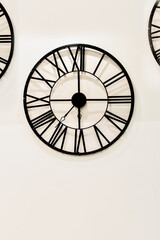 Round forged vintage clock on wall. Antique clock on background of light wall. Abstract background with clock