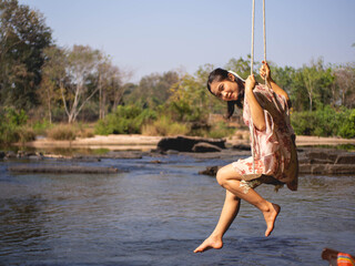 Woman on a wooden swing and a river