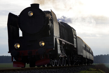 Fototapeta na wymiar Retro smoky steam locomotive on the former railway line