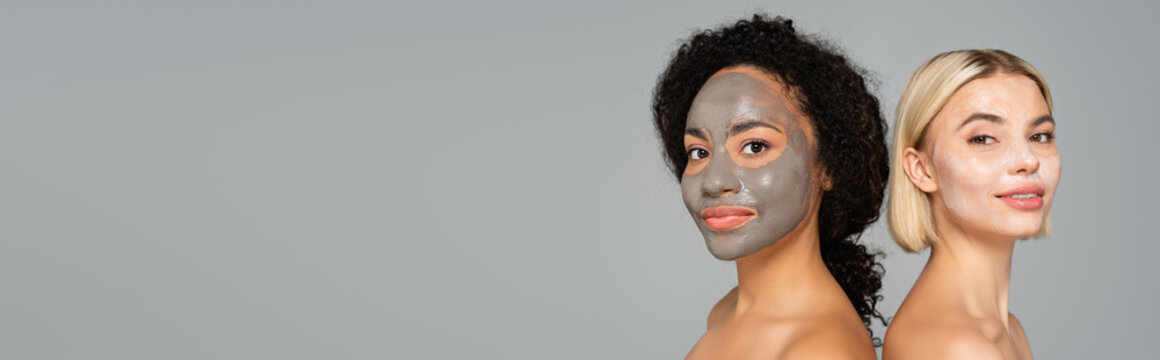 Multiethnic Women With Naked Shoulders And Facial Masks Looking At Camera Isolated On Grey, Banner