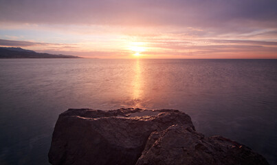 Beautiful sunrise on the sea with rocks in the foreground. Views from Torre del Mar beach.