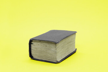 Old thick book with gray shabby cover on yellow background. Space for text. Concept: education,...