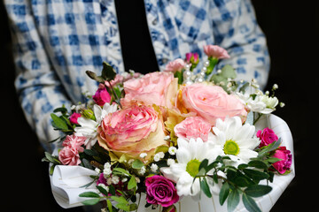 Man gives flowers. Gift box with flowers. Close up of box with pink roses in male hands. Male give gift for mother's day, valentines, women day, birthday. Selective focus