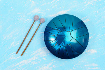 hang musical instrument, glucophone. metal tongue drum, blue background. top view copy space