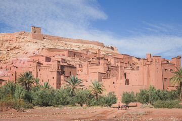 Obraz premium Scenic view of oasis old town Ait Benhaddou, Morocco a historic fortified village, noted for its ancient clay earthen architecture with a distant local Moroccan man and his pack mule.