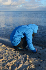 Kind am Meer im Winter sammelt Steine