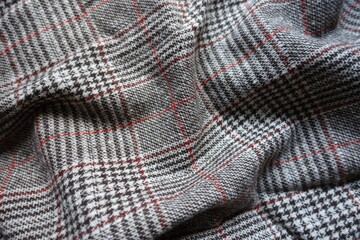 White, grey and red Glen check woolen fabric in soft folds