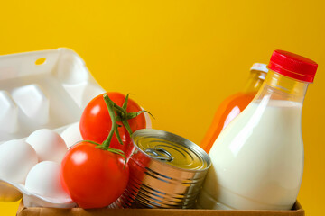 Set of food in a box on a yellow background. Food donations during quarantine and coronavirus.
