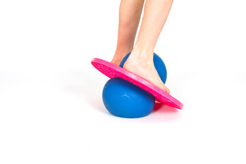 Kids legs on balance trainer isolated on white background. Bouncy ball as a fitness equipment.