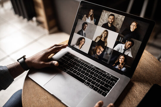 Young African American businessman looks into the laptop screen, speaks by video communication with his colleagues. Business entrepreneur, sitting in an office, pondering a business plan.