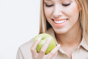 Healthy young woman with perfect teeth holding a green apple