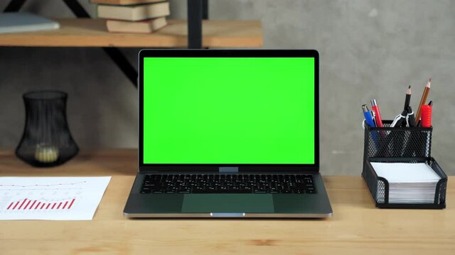 Modern laptop computer display with mock up chroma key green screen standing on table working office business workplace