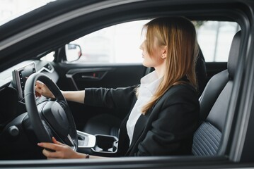 Young beautiful woman showing her love to a car in a car showroom