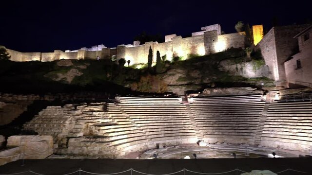View of the roman theatre of Malaga, Spain at night. The Alcazaba, the arabic castle in the background.