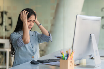 Asian businesswoman gets stressed while having a problem at work in the office.