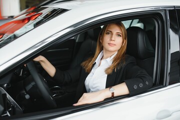 Young beautiful woman showing her love to a car in a car showroom